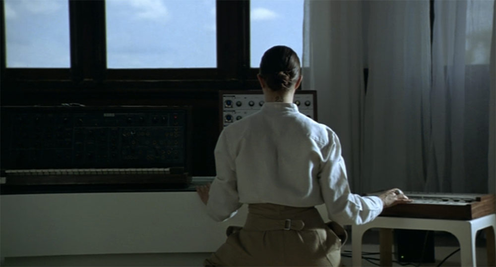 Fig. 6: Et af gruppens medlemmer (Asia Argento) spiller på synthesizer for nogle mennesker, der ligger udenfor i haven.