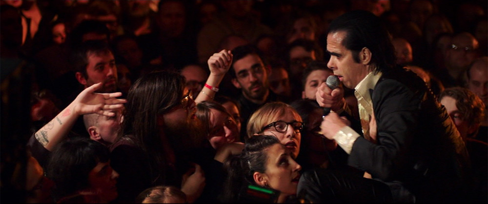 Fig. 9. Nick Cave fører i en smuk samhørighed hånden fra en kvindelig fan op til sit hjerte, mens han i musikken spørger ”Can you feel my heartbeat?”