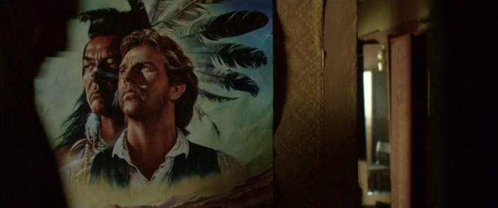 Figur 27: Et set-up og endnu et eksempel på den fortælleøkonomi, der præger scenen: Kevin Costners betydning for Stanislav introduceres via denne indstilling af plakaten for Dances with Wolves (1990).