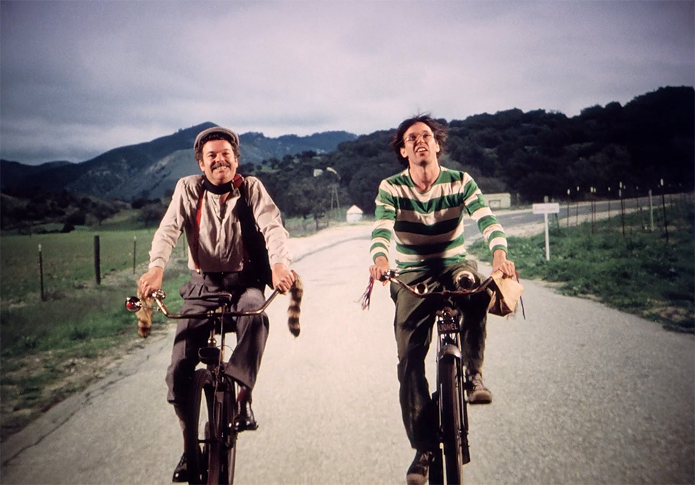 Fig. 7: Hovedfortællingen i Human Highway om livet på dineren og benzintanken nær det lokale atomkraftværk er ren Morten Korch. Her er det Neil Young som tankpasseren Lionel Switch og hans kollega Fred Kelly (spillet af Russ Tamblyn a.k.a. Dr. Lawrence Jacobi fra Twin Peaks og bandelederen Riff fra West Side Story) cyklende på vej til arbejde.