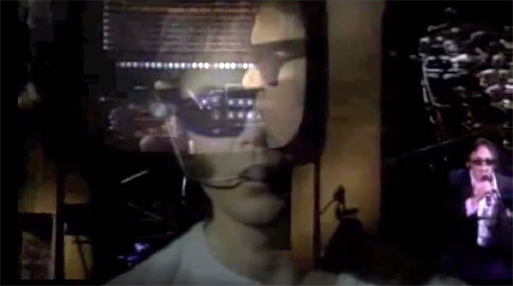 Fig. 12: ”Mr. Soul” bliver fortolket med robotstemme og hypermedieret billedside, hvor Youngs performance live og på scenens gigantiske tv-skærm overlapper hinanden i en dobbelteksponering.